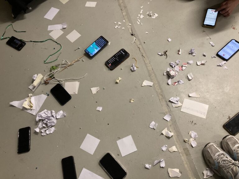 Home Floor littered with paper bits, phones, tennis shoes, the result of performing a text score called Papericity by Pauline Oliveros by students of BEAR, which stands for Base for Experiment, Art & Research, which is the practice-based Bachelor of Fine Art program at ArtEZ University of the Arts in Arnhem.